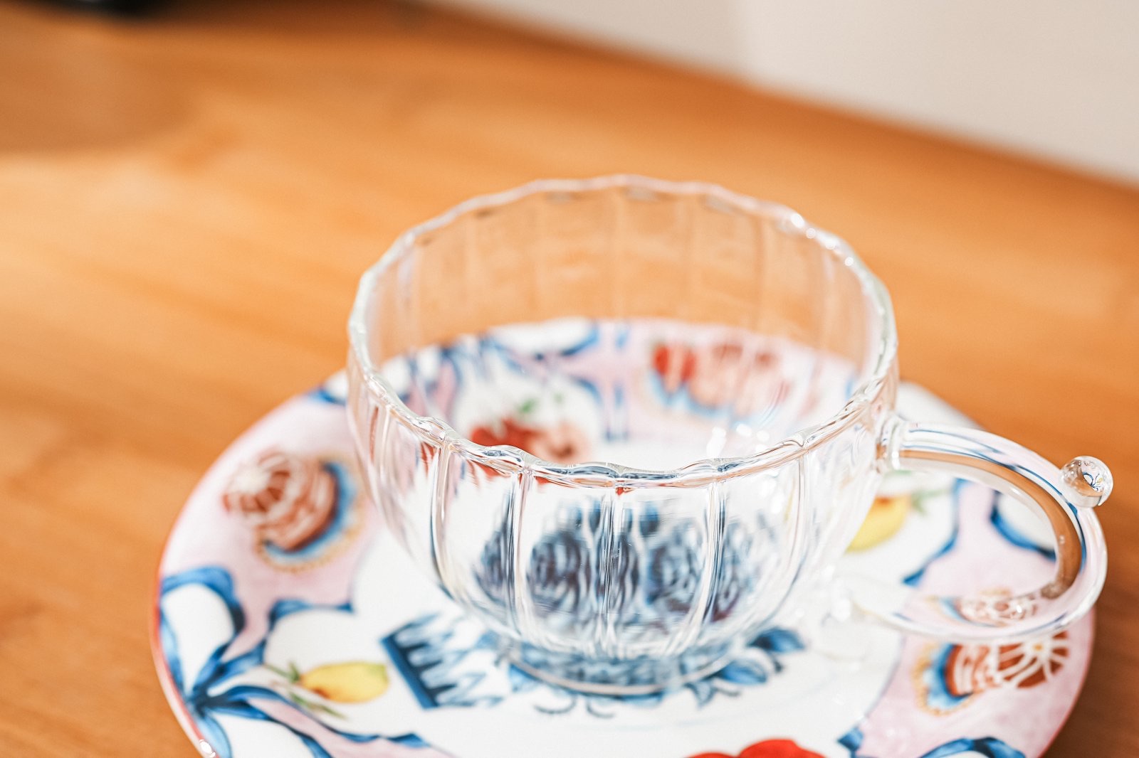 Glass cup and painted saucer on a wooden table